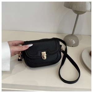 Detail of black lychee grain leather saddle bag with a golden metal twist lock clasp