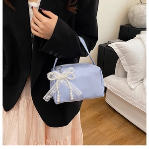 Detail of light blue underarm bag featuring delicate lace bow and pearl tassels with fine handle