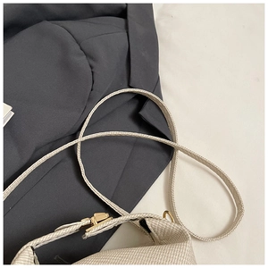 Close-up of minimalist beige fabric crossbody bag featuring a golden metal clasp