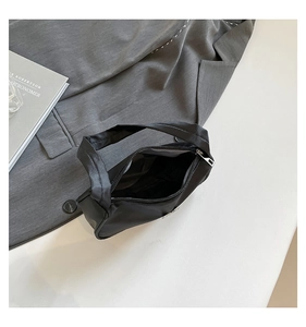 Detail view of the black nylon shoulder bag with silver zipper and spacious interior