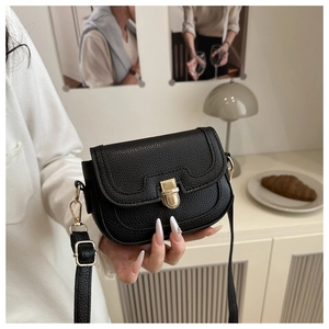 Close-up of black crossbody bag with golden metal push-lock and lychee texture