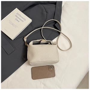 Minimalist woven crossbody bag with gold hardware and slim strap shown with smartphone