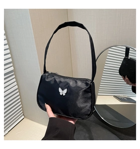Detail of a black nylon shoulder bag featuring a 3D white butterfly ornament detail