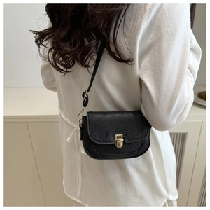 Detail of black pebbled leather crossbody bag with vintage gold metal lock and strap