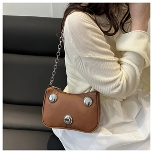 Chic brown dumpling bag with silver studs and chain strap shown on a model