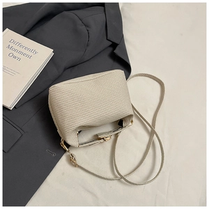 Detail of cream woven pillow bag with gold hardware on grey suit background