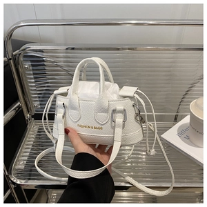 Detailed macro view of white mini shell bag with gold fashion lettering and thin strap