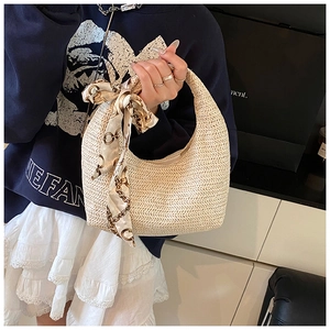 Détail d'un sac hobo tissé beige avec un foulard en soie décoratif sur la poignée