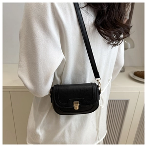 Side view of a black pebble leather crossbody bag with golden buckle on a model