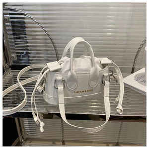 Detail of white mini shell bag with lychee grain texture and golden fashion text