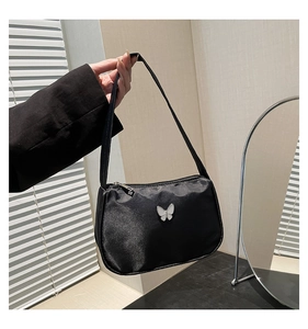Close-up of black nylon shoulder bag featuring a decorative silver metal butterfly buckle