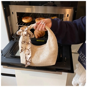 Détail du sac à main hobo tressé beige avec un foulard en soie décoratif sur l'anse