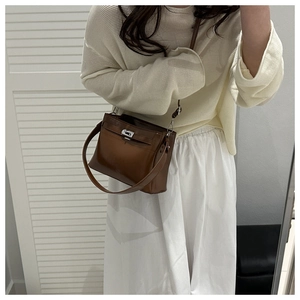 Close-up of brown glossy leather tote bag with silver metal turn-lock and stitching