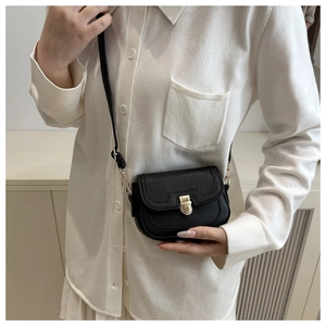 Detail of black textured leather saddle bag with gold buckle and wavy flap design