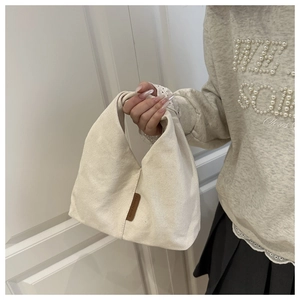 Détail du sac à main en toile beige minimaliste avec étiquette en cuir à la main