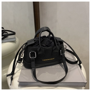Detail of black crossbody bag with litchi grain texture and gold fashion lettering