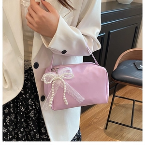 Close-up of lilac handbag featuring a white lace bow and elegant pearl embellishments