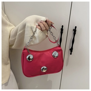 Detail of fuchsia crescent bag with large silver studs and metallic chain strap