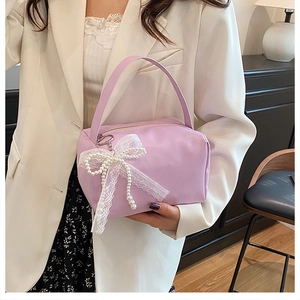 Detailed view of lavender handbag featuring a decorative pearl lace bow and top handle