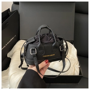 Detail of mini black lychee texture shell bag with golden logo and gift box