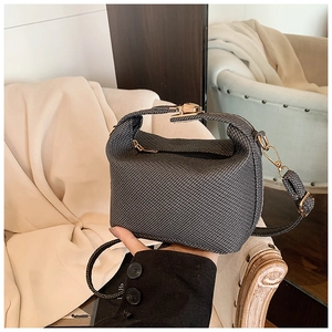 Detail of grey mini bag featuring woven texture fabric and premium gold-tone hardware