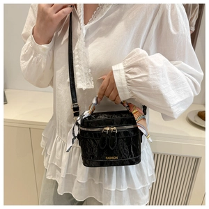 Detail of black pleated crossbody bag with 'FASHION' text and silk scarf on handle