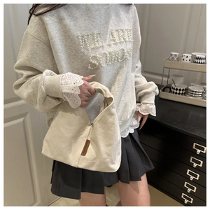Détail d'un sac cabas en toile blanc cassé avec étiquette en cuir sur tenue décontractée