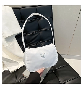 Detail shot of a white nylon underarm bag with a silver butterfly metal ornament