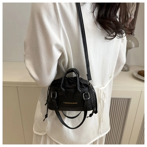 Close-up of black lychee texture leather bag with drawstring and gold logo detail