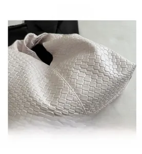 Detailed close-up of cream woven leather texture and side seams of a stylish hobo bag