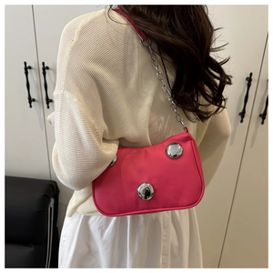 Detailed view of pink crescent bag with large silver rivets and delicate chain strap