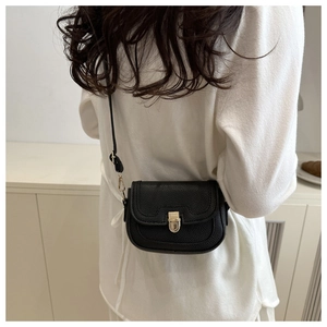 Detailed back view of model wearing black litchi pattern crossbody bag with gold hardware
