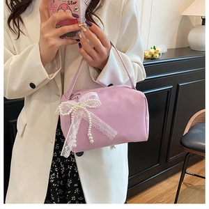 Detail of light purple handbag featuring a white lace bow and elegant pearl tassel