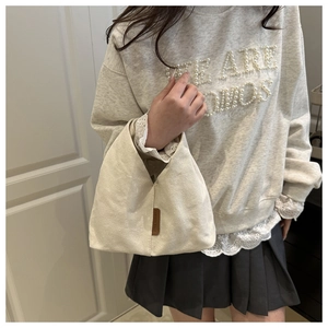 Détail du sac à nœud en toile crème avec étiquette en cuir et texture textile
