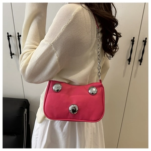Hot pink baguette bag with large silver spherical ornaments on model's shoulder