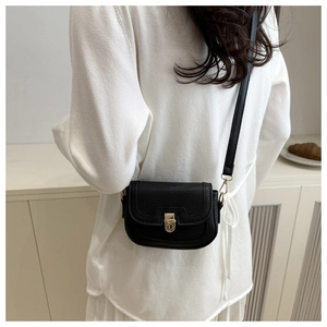Détail du sac de selle noir en cuir grainé avec boucle en métal doré sur le modèle