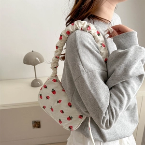 White corduroy shoulder bag with strawberry prints and a ruched cloud strap on a model