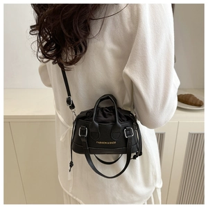 Model wearing black pebble leather mini crossbody bag with drawstring closure detail