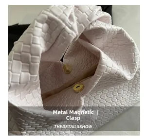 Detailed macro view of woven leather texture with gold magnetic metal closure buckle