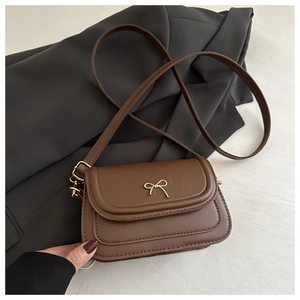 Close-up of brown vintage square bag with gold bow clasp on a white marble surface