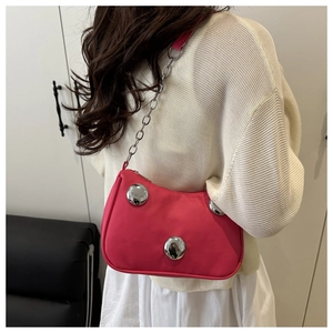 Detail of rose red shoulder bag featuring large silver metal studs and a chain strap