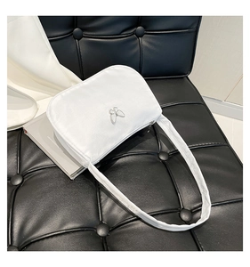 Close-up of white padded hobo bag with silver butterfly buckle on black leather background