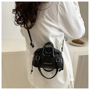 Close-up of black mini shell bag with litchi grain texture and adjustable shoulder strap