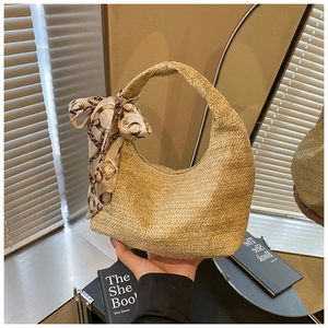 Détail du sac hobo en paille tissée avec un foulard décoratif en soie et motif de chaîne