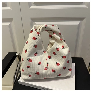 Détail du sac à nœud en velours côtelé blanc cassé avec motifs fraises sur boîte blanche