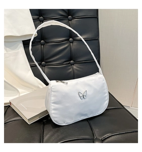 Detail of white nylon shoulder bag with silver butterfly emblem on a black leather chair