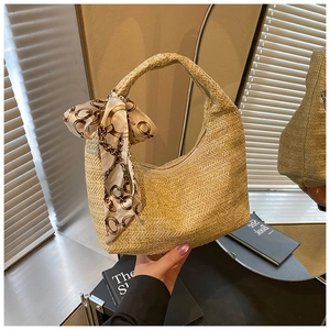 Détails de texture du sac en paille tissé main avec poignée ornée d'un foulard en soie