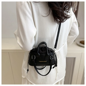 Detail of black pebbled leather mini bucket bag with gold lettering and silver hardware