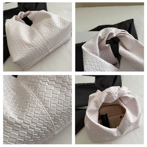 Detail view of pink woven dumpling bag with knot handle and interior storage capacity