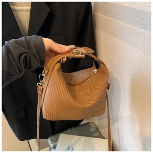 Close-up of brown woven texture handbag with golden lock and adjustable strap